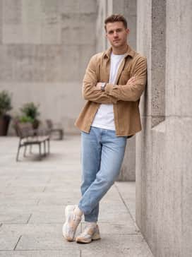 Air Pegasus Wave Premium – An urban casual outfit consisting of light-wash tapered denim jeans, a crisp white oversized t-shirt, and an unbuttoned tan corduroy shirt to pull from the shoe's warm earthy tones.