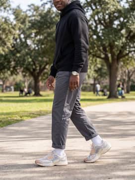 A minimalist streetwear set with charcoal grey nylon track pants, a black boxy-fit hoodie, and high-quality white crew socks pulled up to emphasize the shoe's sleek silhouette.