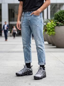 Distressed light-wash straight-leg jeans with a tucked-in black graphic tee and a silver utility chain to complement the metallic grey tones.