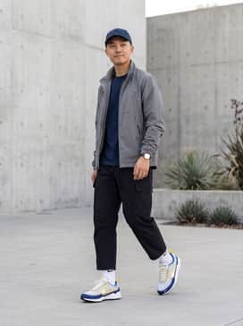 Air Zoom Spiridon Sp – A techwear-inspired look featuring tapered black cargo pants, a technical grey windbreaker, and a navy blue baseball cap to echo the shoe's primary color.