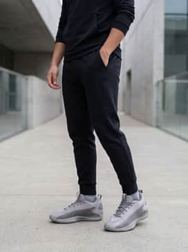 Black tapered tech-fleece joggers paired with a matching slim-fit performance hoodie for a sleek and functional athleisure look.