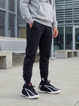Tapered black jogger pants with a graphic grey hoodie and a red beanie that picks up the subtle color accents on the tongue and heel.