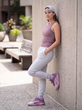 Aone Dog Mom – Light heather grey tapered joggers and a tucked-in mauve ribbed tank top, accessorized with a simple baseball cap for a clean, sporty vibe.