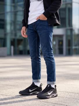 Aone – Tapered dark indigo slim jeans worn with a crisp white graphic t-shirt and a classic black zip-up hoodie for a cool, everyday school outfit.