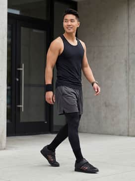 High-performance black compression leggings worn under charcoal mesh training shorts, paired with a fitted moisture-wicking racerback tank top for maximum mobility during heavy lifts.