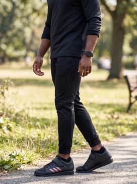 A sleek monochromatic look featuring slim-fit black track pants with side stripes, a matching quarter-zip training pullover, and performance-grade no-show socks.