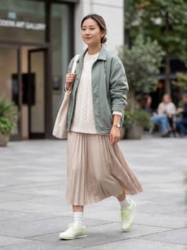 A white pleated tennis skirt paired with an oversized cream cable-knit sweater and slouchy white crew socks for a soft, preppy look.