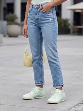High-waisted light wash straight-leg denim jeans worn with a cropped pastel graphic baby tee and a small nylon shoulder bag.