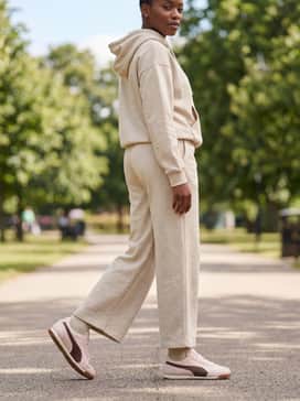 A beige monochromatic loungewear set consisting of wide-leg sweatpants and a matching hoodie for a luxurious yet relaxed athleisure ensemble.