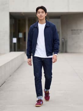 Slim-fit indigo denim jeans paired with a crisp white T-shirt and a navy blue Harrington jacket for a classic, subculture-inspired look.