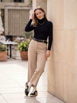 Astrograbber Leather – Beige wide-leg trousers combined with a fitted black turtleneck and gold statement jewelry for an elevated office-ready ensemble.