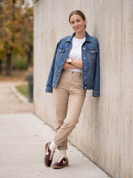 Beige high-waisted chino trousers with a tucked-in white graphic t-shirt and an unbuttoned denim jacket for a relaxed, heritage-inspired weekend look.