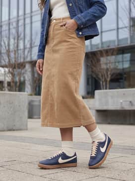 Astrograbber Leather – A tan corduroy midi skirt paired with a fitted ivory ribbed turtleneck and a structured denim jacket to play up the vintage textures and colors.