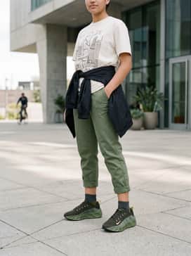 Slim-fit olive green joggers and a crisp white heavyweight graphic tee, finished with a matte black windbreaker for a cohesive, athletic aesthetic.