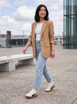 Light-wash straight-leg jeans paired with a ribbed white tank top and an oversized tan blazer for a balanced, polished-casual look.