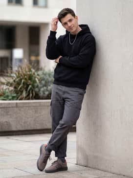 Barreda Decode Shoes Audi Revolut F1 Team Shoes – A modern streetwear outfit consisting of charcoal cargo pants, an oversized black hoodie, and a silver box-chain necklace.