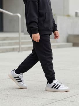 Barreda Decode Shoes Children – A monochromatic black athletic set featuring slim-fit joggers and a zip-up hoodie to let the metallic silver pop.