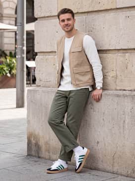 Olive green cargo pants and a beige utility vest over a long-sleeve white waffle-knit shirt for an outdoor-inspired lifestyle aesthetic.