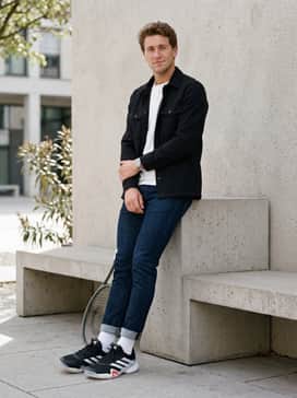 Slim-fit dark-wash tapered jeans worn with a simple white premium cotton t-shirt and an unbuttoned black utility overshirt for a polished street style.