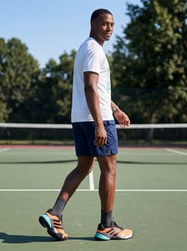 A casual weekend kit pairing navy blue mesh shorts with a breathable white graphic tee that features subtle teal accents to pull the look together.