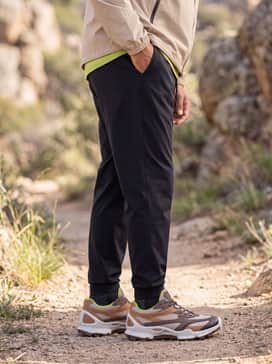 Biom Ctrail – Tapered black water-resistant joggers combined with a beige lightweight windbreaker and a lime green baseball cap to highlight the shoe's accent color.