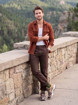 Biom Ctrail – Dark wash utility pants worn with a rust-colored flannel shirt over a white ribbed tank top for a rugged, everyday outdoor aesthetic.