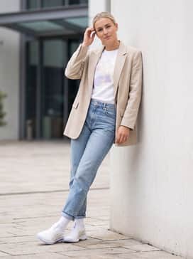 Straight-leg light wash jeans with a tucked-in graphic tee and an oversized beige blazer for a clean, streetwear-inspired look.