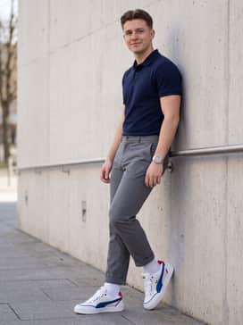 Tailored grey chinos worn with a navy blue polo shirt and a silver-tone sports watch for a smart-casual aesthetic.