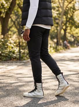 Box Hog 4 Shoes – A high-contrast fashion-forward look with slim-fit black stacked joggers, a white long-sleeve thermal top, and a matte black puffer vest for a layered transitional weather style.