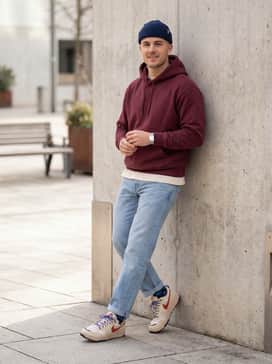 Light wash distressed straight-leg jeans worn with an oversized burgundy graphic hoodie and a navy knit beanie to complement the shoe's accent colors.