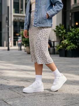 A floral-print midi skirt paired with a fitted white ribbed tank top and a light denim jacket to create a feminine yet grounded ensemble.