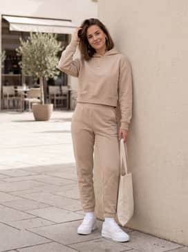 Tapered beige joggers, a matching cropped hoodie, and gold hoop earrings for a coordinated and elevated athleisure vibe.