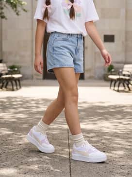 Cali Court Summer Feels – High-waisted, light-wash denim shorts paired with a tucked-in oversized white graphic tee and pastel pink hair ribbons for a coordinated look.