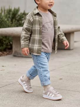 Light-wash straight-leg denim jeans cuffed at the ankle, paired with a soft cotton graphic t-shirt and an unbuttoned flannel shirt for a cool, vintage skate vibe.