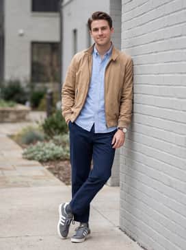 Tapered navy chinos and a tucked-in light blue Oxford shirt under a tan harrington jacket for a polished, creative office vibe.