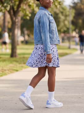 A ditsy floral print mini dress in shades of lilac and white, accessorized with a simple denim jacket and minimalist silver jewelry.