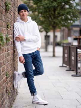Slim-fit olive green cargo pants tucked slightly into the tops of the shoes, styled with a crisp white hoodie and a black beanie.