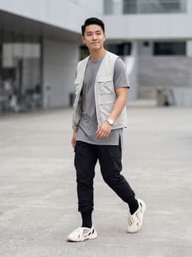 A techwear-inspired look featuring black tapered cargo joggers, a grey long-line breathable t-shirt, and a lightweight nylon utility vest for a functional, futuristic aesthetic.