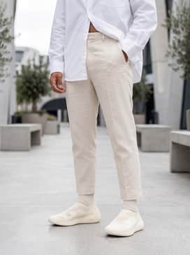 A clean summer ensemble consisting of cream-colored linen shorts and an oversized white poplin button-up shirt worn open over a ribbed tank top.