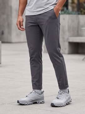 Slim-fit charcoal chinos with a crisp white performance button-down shirt and a lightweight technical mac coat for a commute-ready aesthetic.