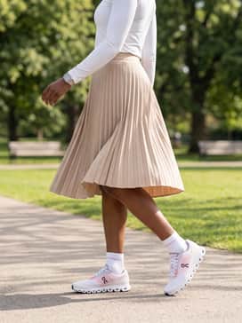 Cloud 6 Push – A beige technical pleated skirt paired with a fitted white long-sleeve performance top for a sporty yet feminine ensemble perfect for errands or brunch.
