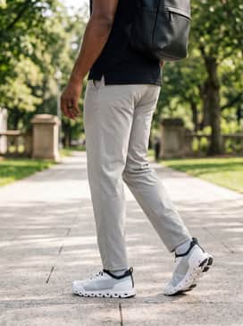 Light grey chinos combined with a black polo shirt and a minimalist leather backpack for a smart-casual office environment.