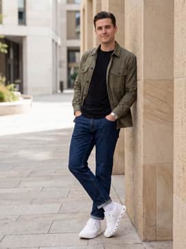 Straight-leg indigo denim jeans, a simple black crewneck t-shirt, and an unbuttoned olive green utility shirt for an effortless urban aesthetic.