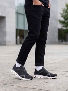 A streetwear-inspired ensemble with slim-fit black denim jeans, a premium oversized grey hoodie, and a minimalist black baseball cap for a cohesive tonal aesthetic.