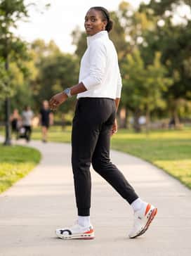Elevated warm-up ensemble featuring tapered black tech-fleece joggers, a white quarter-zip training pullover, and a minimalist technical running cap.