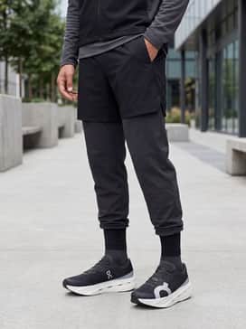 A winter training look with compression-fit running tights, a quarter-zip thermal mid-layer, and a wind-resistant technical vest in charcoal.