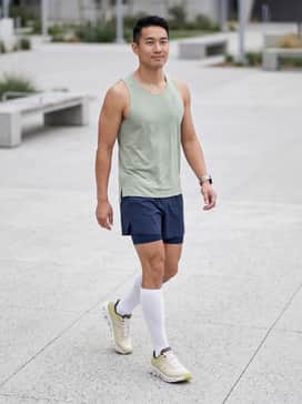 Cloudflow 4 – A pair of 5-inch split running shorts in navy blue paired with a laser-cut, moisture-wicking tank top in light sage green and white crew-length compression socks.