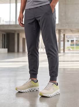 Tapered charcoal grey technical joggers and a fitted black long-sleeve performance base layer with a quarter-zip collar for cooler morning runs.