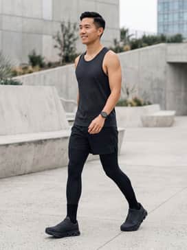 A high-performance athletic look featuring moisture-wicking compression tights under lightweight black running shorts, paired with a fitted technical mesh singlet in charcoal grey.