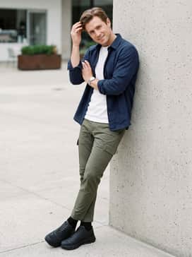 A polished casual outfit consisting of slim-fit olive green cargo pants, a crisp white heavyweight cotton t-shirt, and an unbuttoned navy blue overshirt for a versatile weekend look.